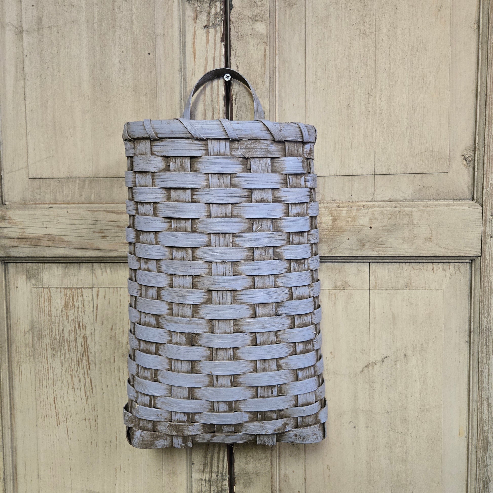 A handwoven door basket in a robins egg blue color, displayed against a wooden background.