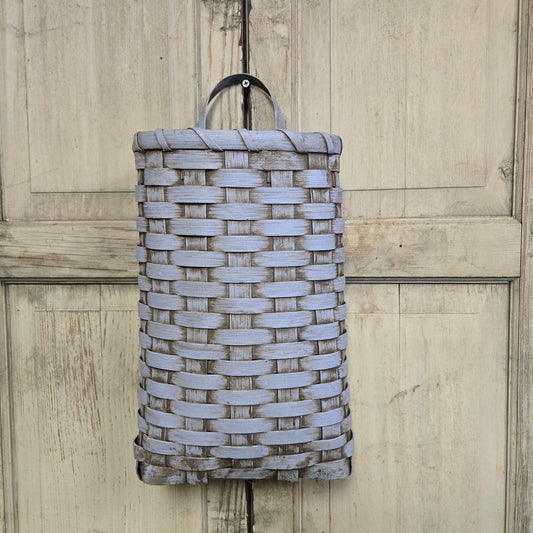 A handwoven door basket in a robins egg blue color, displayed against a wooden background.