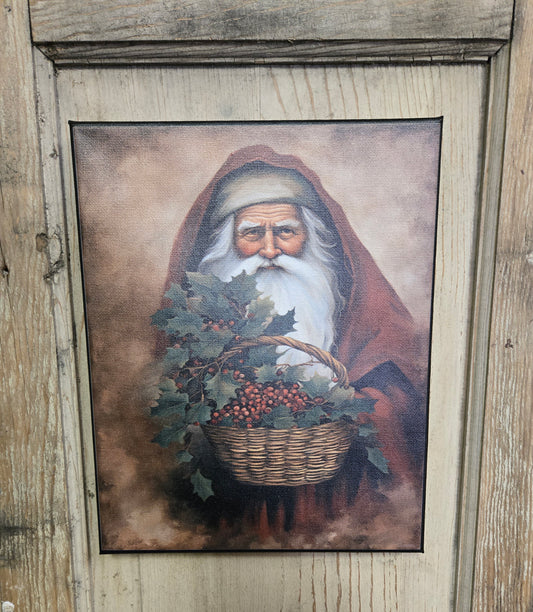 A canvas print featuring a traditional design of Santa Claus with a basket of holly and berries, wearing a red hat and coat, against a wooden background.