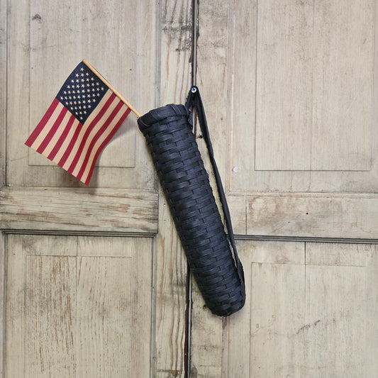 A handwoven blue flag basket placed against a wooden background, with a small American flag positioned next to it.