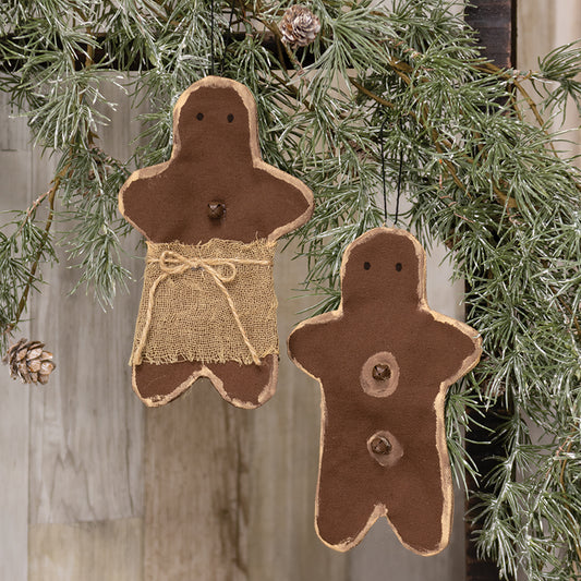 Two rustic gingerbread man ornaments hanging on a Christmas tree.