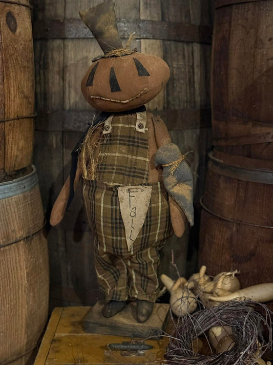 Scarecrow-like figure with a pumpkin head in a rustic setting with wooden barrels.