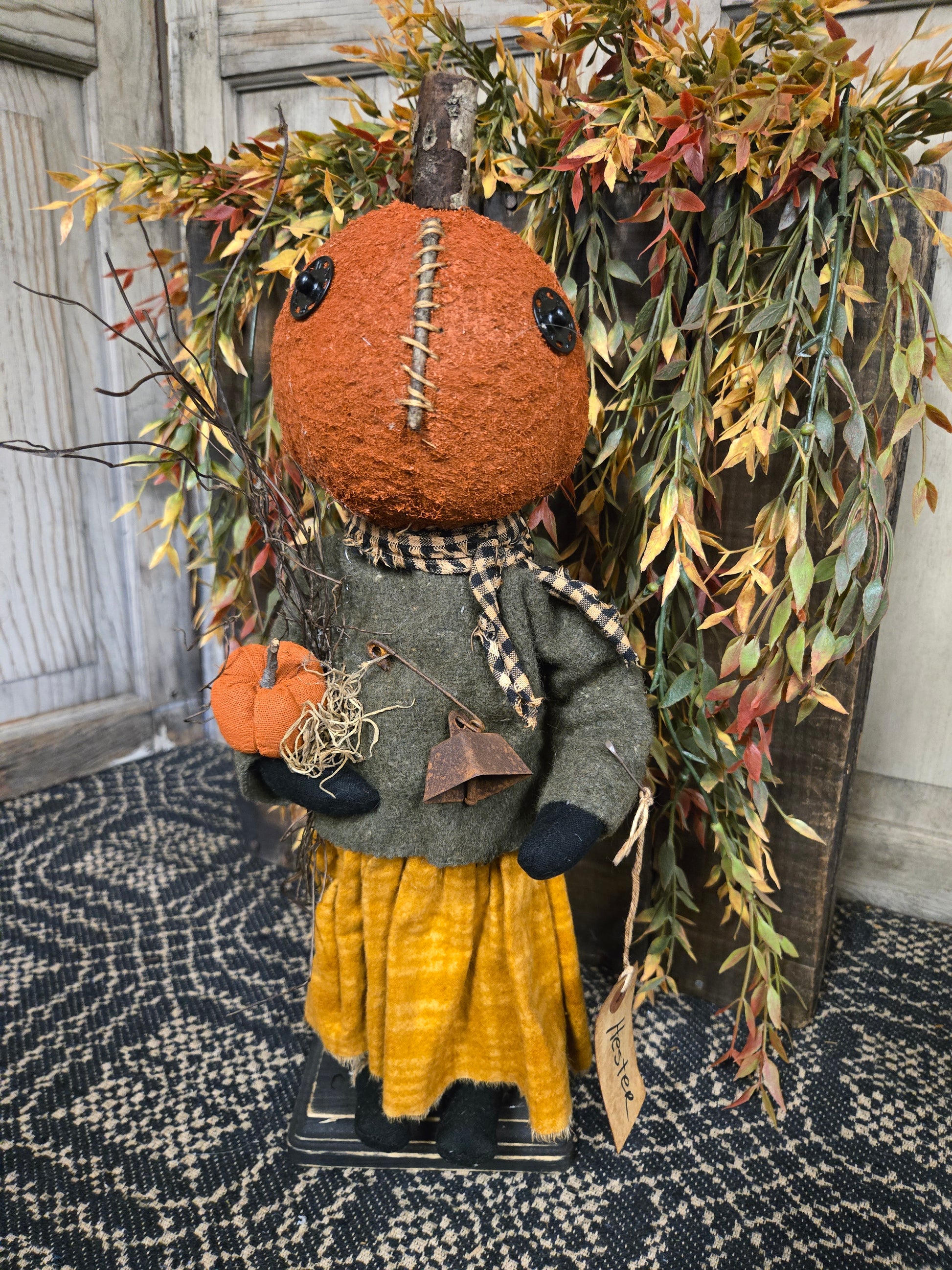 Decorative scarecrow with pumpkin head and autumn leaves on a textured surface
