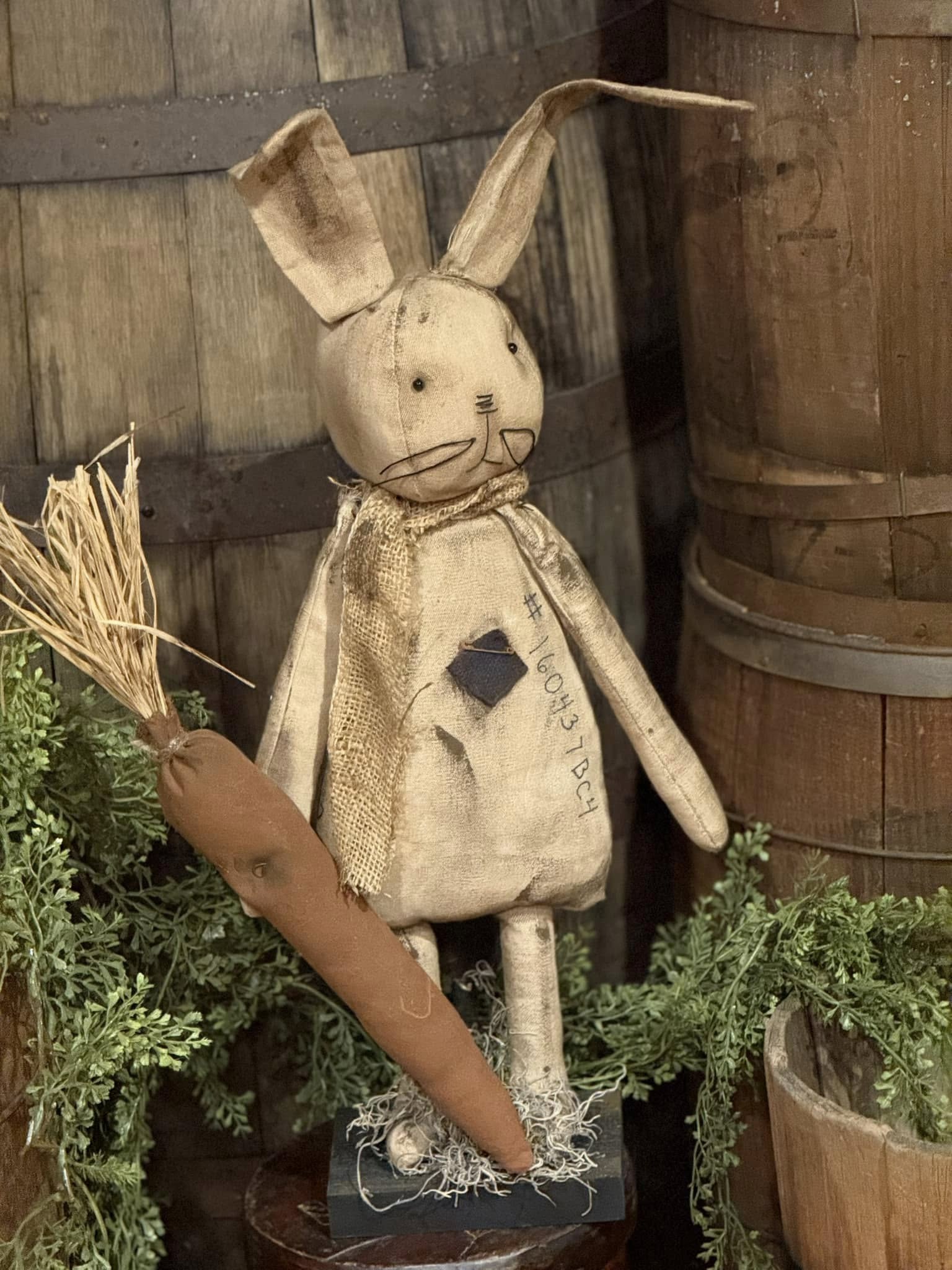A handcrafted beige fabric hop bunny with a carrot, set against a rustic background.