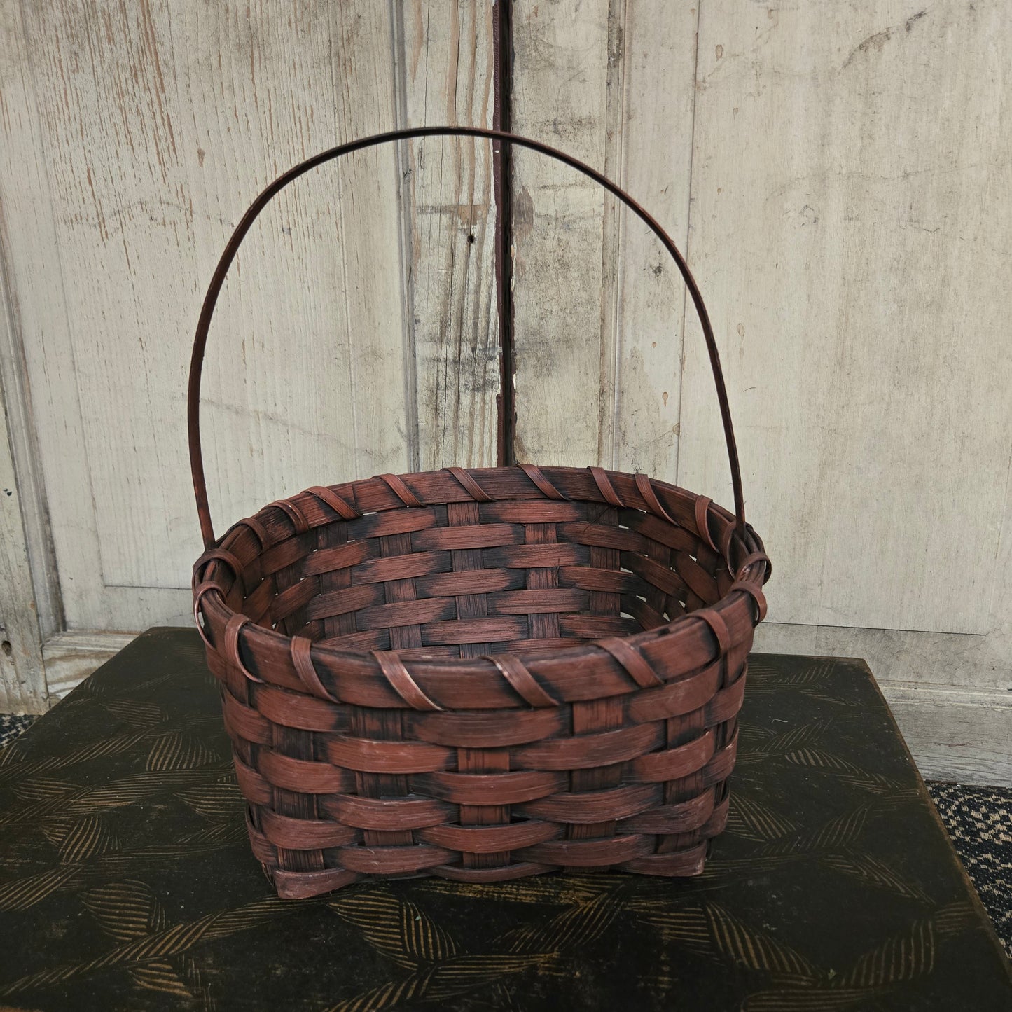 Woven brown basket with a handle on a wooden surface