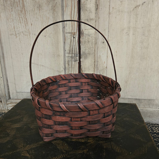 Woven brown basket with a handle on a wooden surface