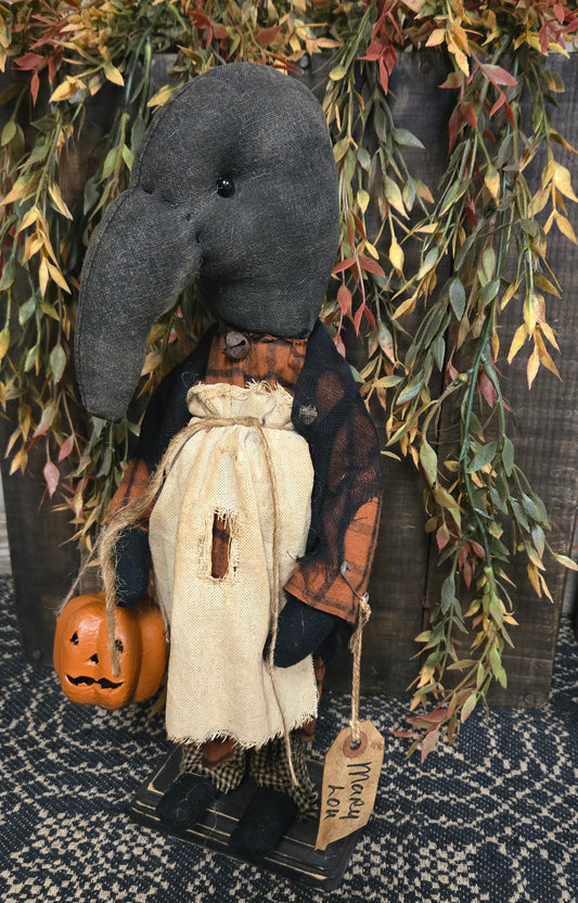 Halloween-themed doll with a tag and pumpkin, surrounded by autumn leaves.