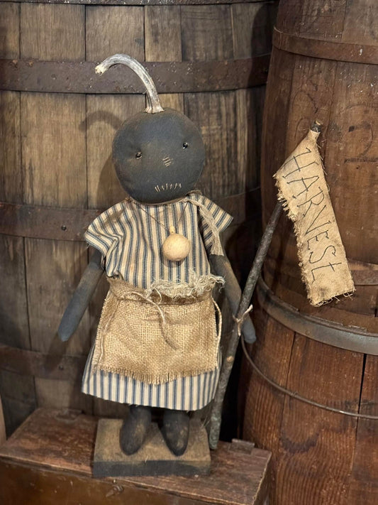 Vintage-style doll with striped dress and apron against a wooden background