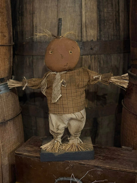 Vintage-style scarecrow figure with plaid shirt and straw body against a rustic wooden background