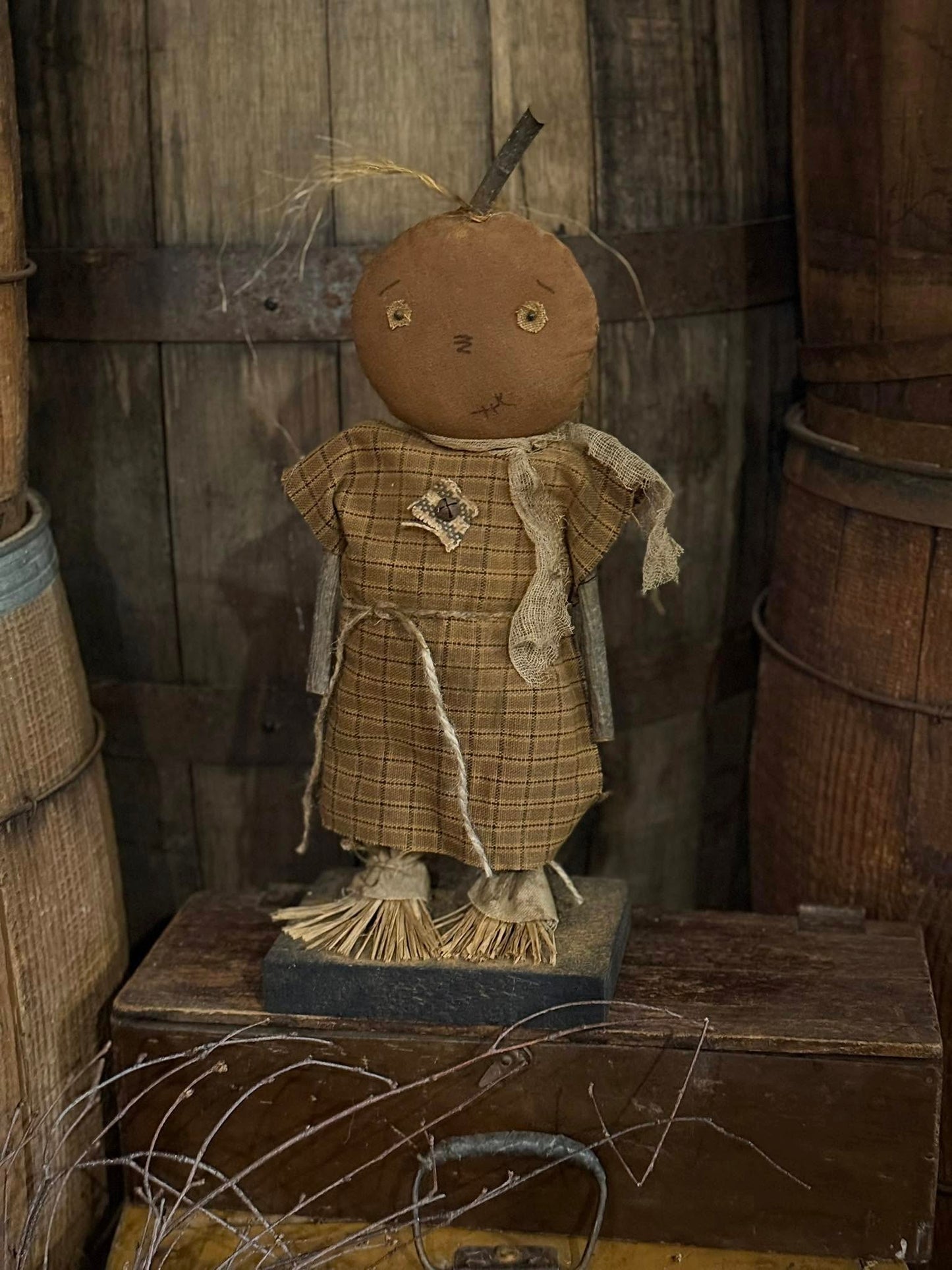 Vintage-style scarecrow figure with a plaid dress in a rustic setting.