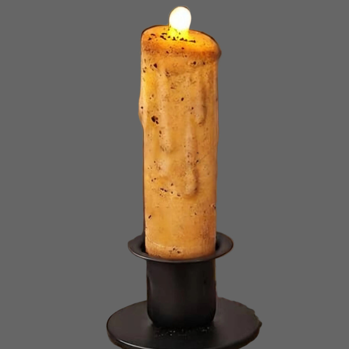 Nubby candle in wrought iron holder on a grey background.