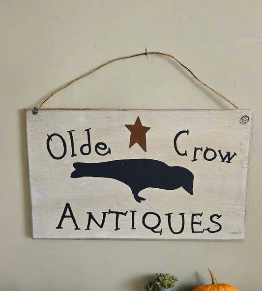 Wooden sign with 'Olde Crow Antiques' text and crow silhouette on a wooden background