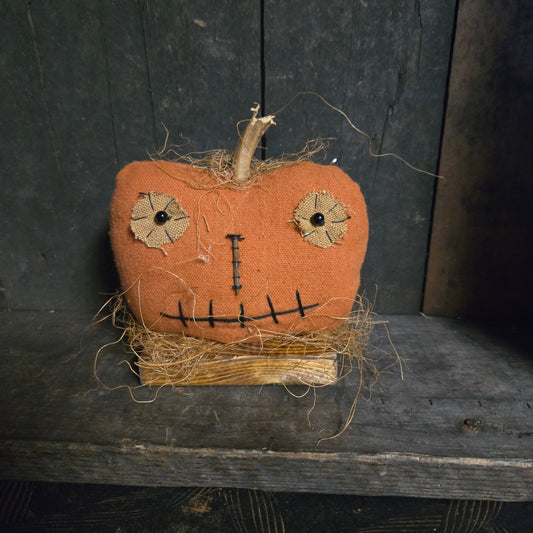 Textured pumpkin decoration with face on a dark wooden surface