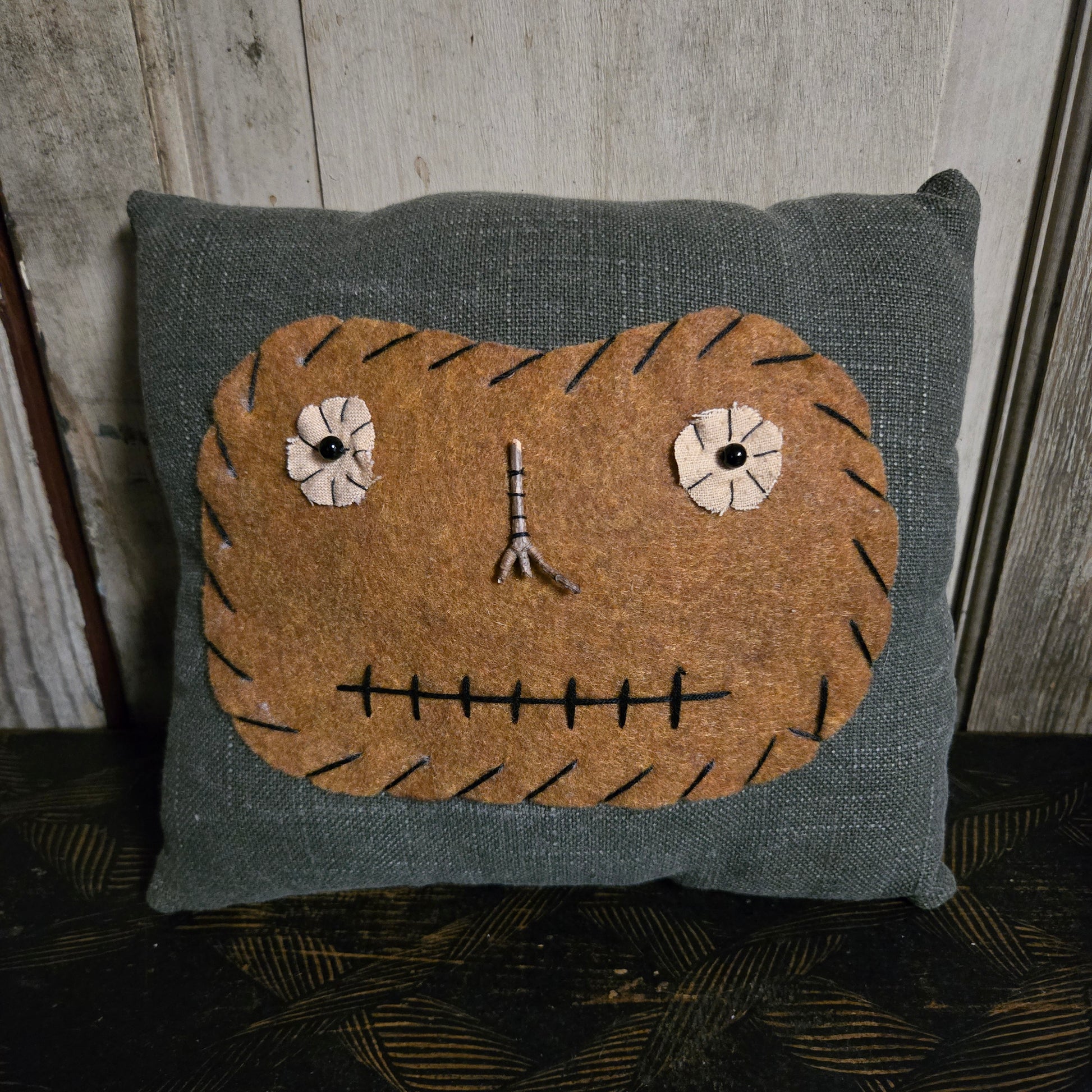 Textile pillow with a face design on a wooden surface