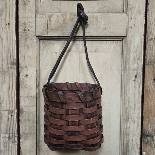 A burgundy basket hanging on a door knob.