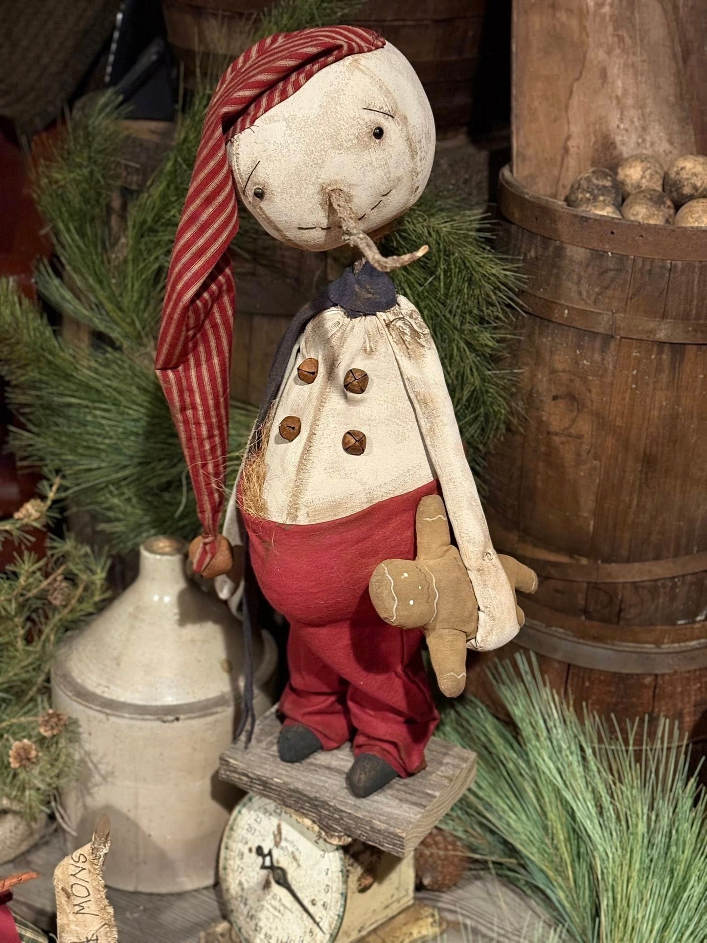 Vintage-style snowman with a striped headscarf and red pants in a rustic setting
