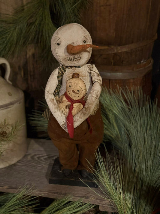 Decorative snowman figurine with a small teddy bear inside, set against a rustic background.