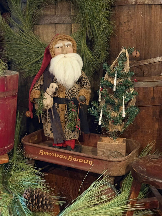 Decorative scene with a Santa holding sheep, small tree, and pinecones on a wooden surface.