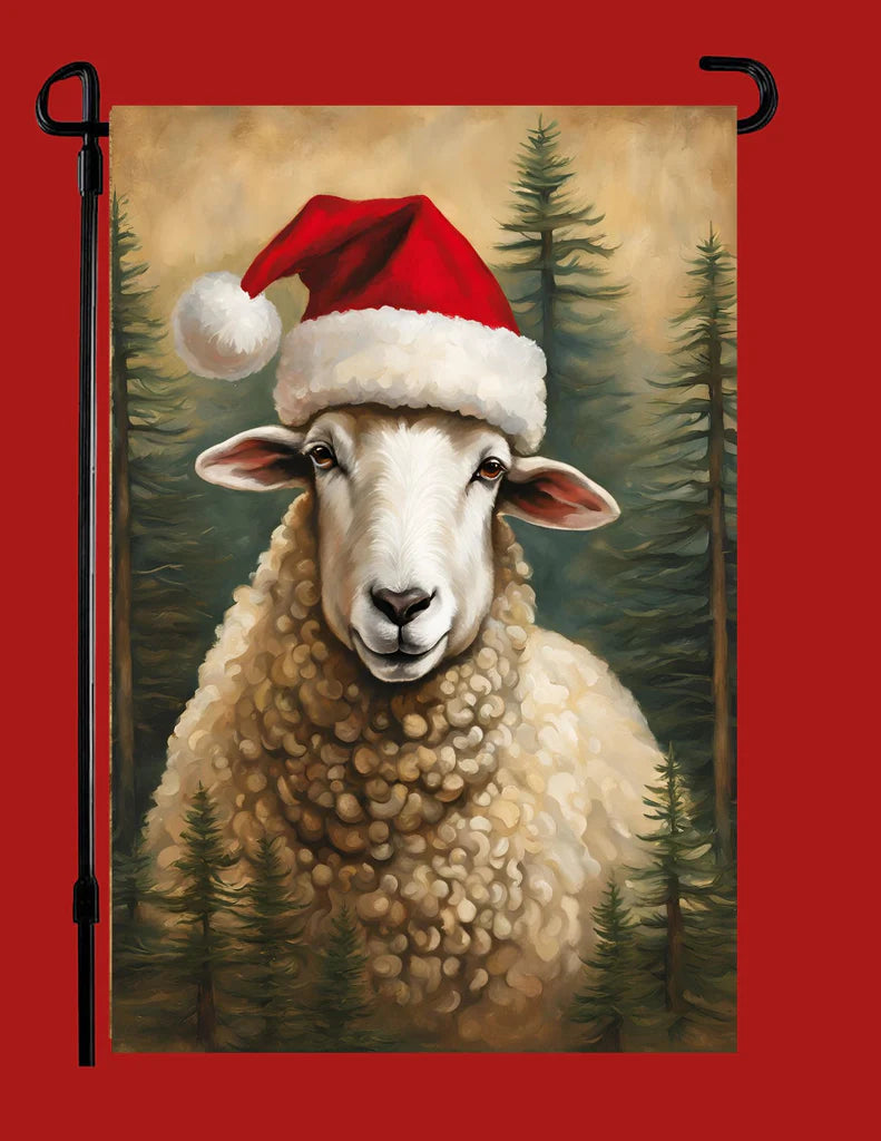 A vertical garden flag featuring a painted sheep in a Santa hat against a forest background, shown hanging on a black metal stand against a solid red backdrop.