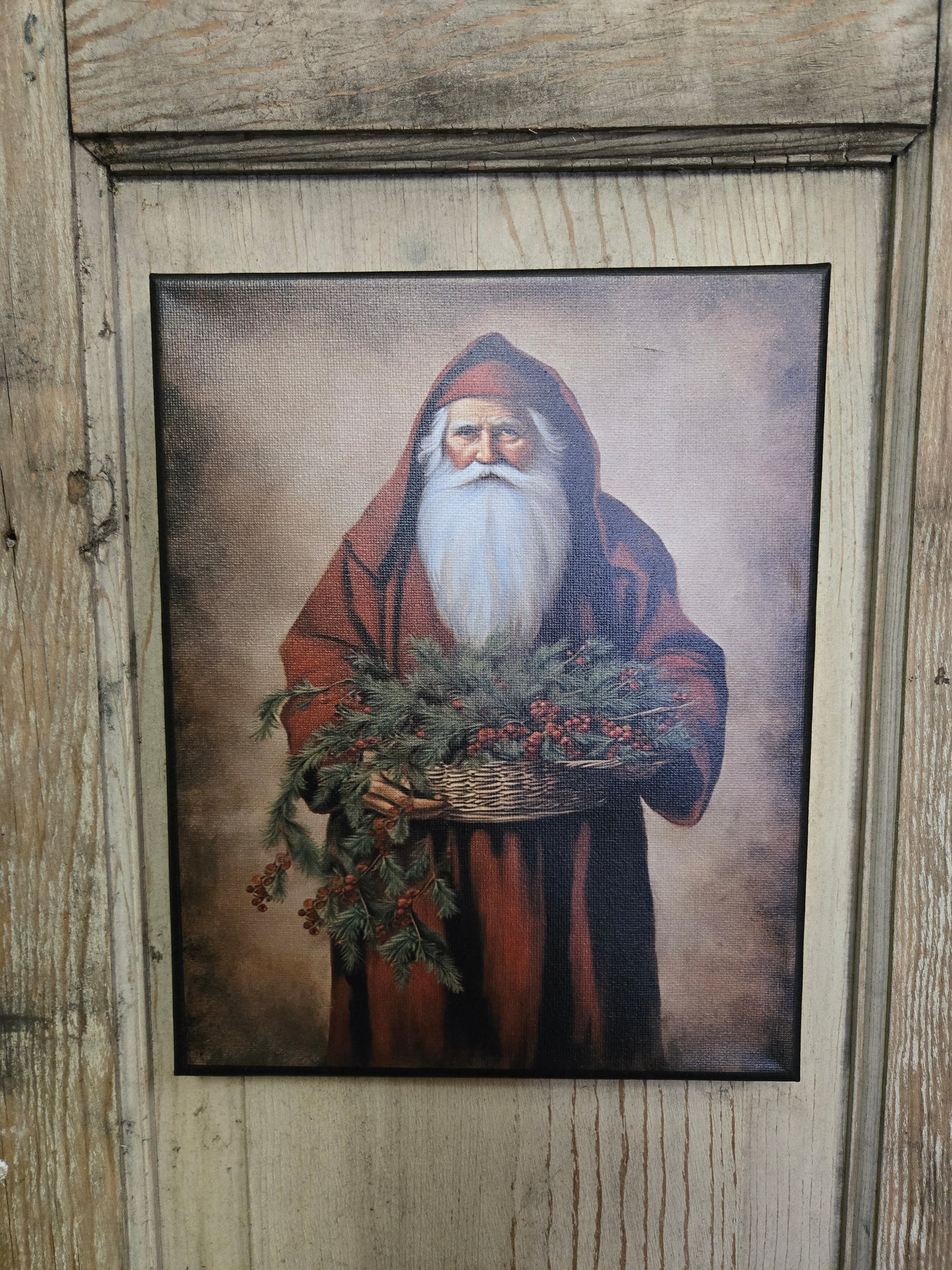 A canvas print featuring a traditional Santa Claus figure holding a basket with greenery.