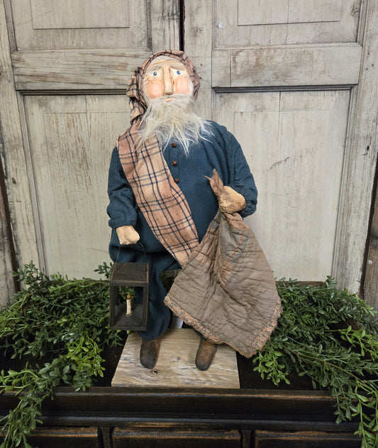 Primitive Santa with Lantern, featuring a traditional lantern and a clay face with a plaid scarf, standing on a platform with holiday decor.