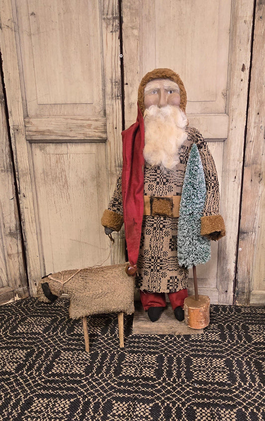 A rustic Santa figurine with a bottlebrush tree and a sheep beside him, placed against a wooden backdrop.