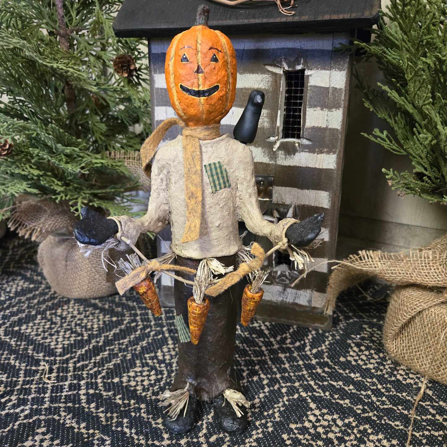 A handcrafted scarecrow with a pumpkin face and a bird perched on its glove, set against a rustic background.