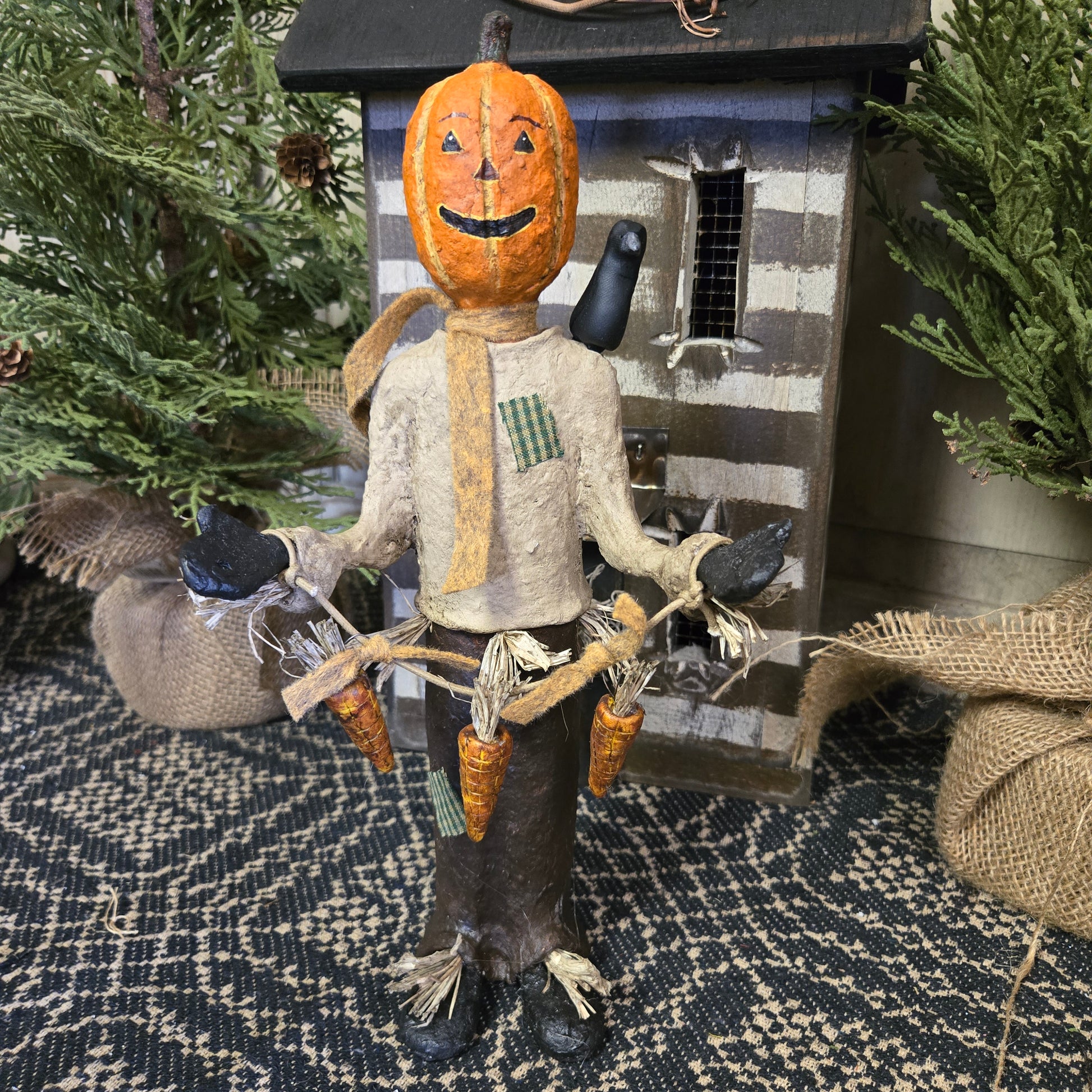 A handcrafted scarecrow with a pumpkin face and a bird perched on its glove, set against a rustic background.