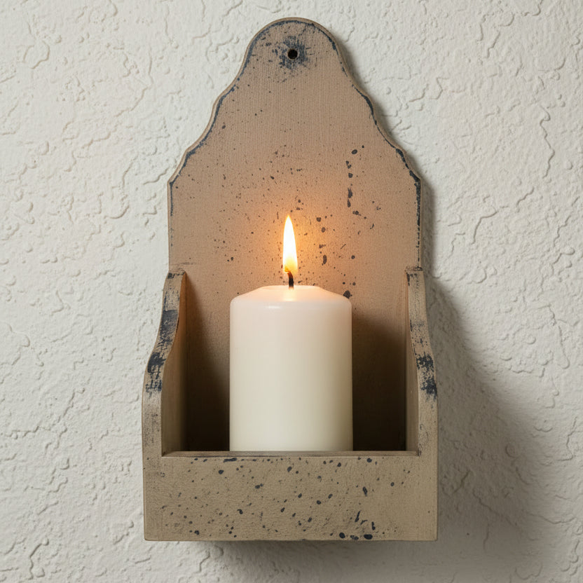 Wall-mounted candle holder with a lit candle on a textured wall