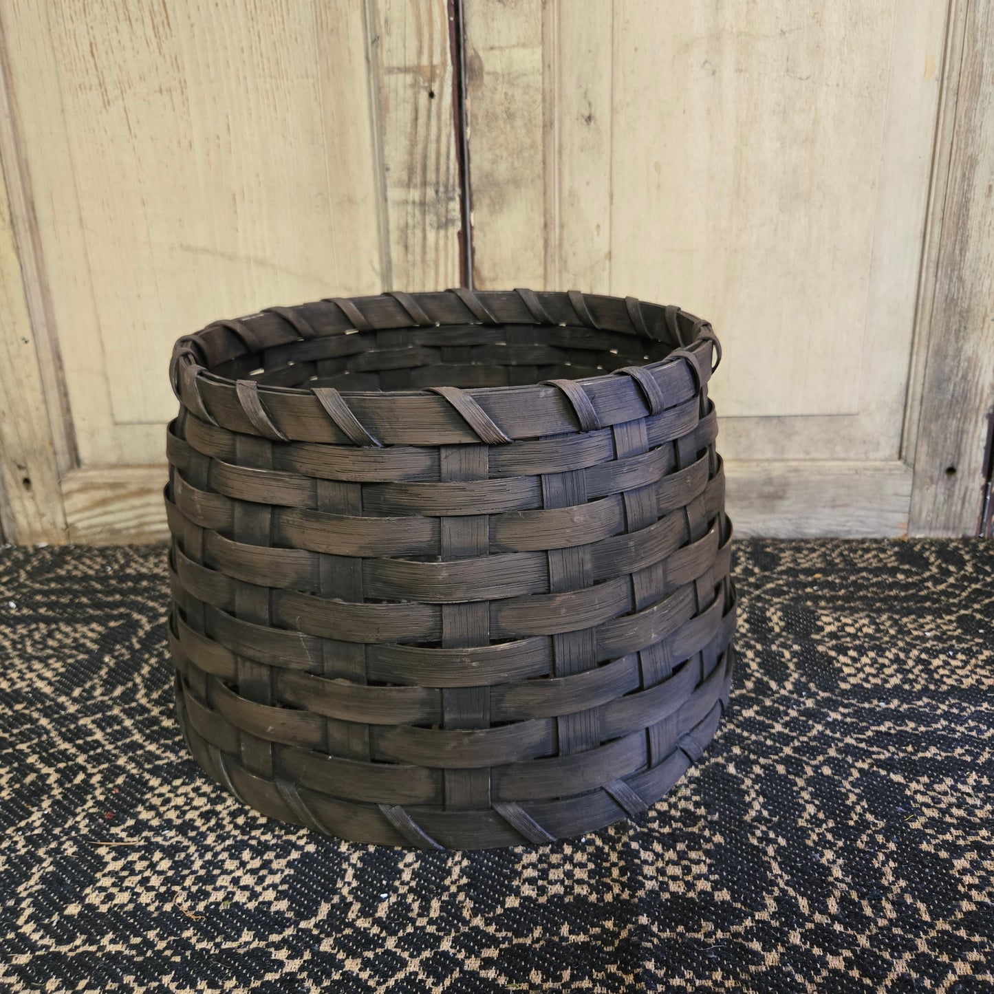 A brown woven basket tree collar on a patterned rug.