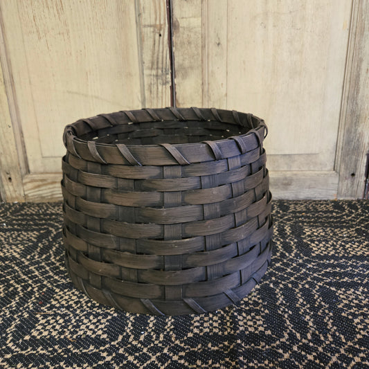 A brown woven basket tree collar on a patterned rug.