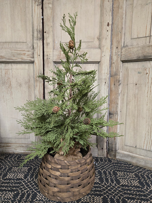 A brown woven tree collar around the base of a natural-looking tree, set against a rustic backdrop.