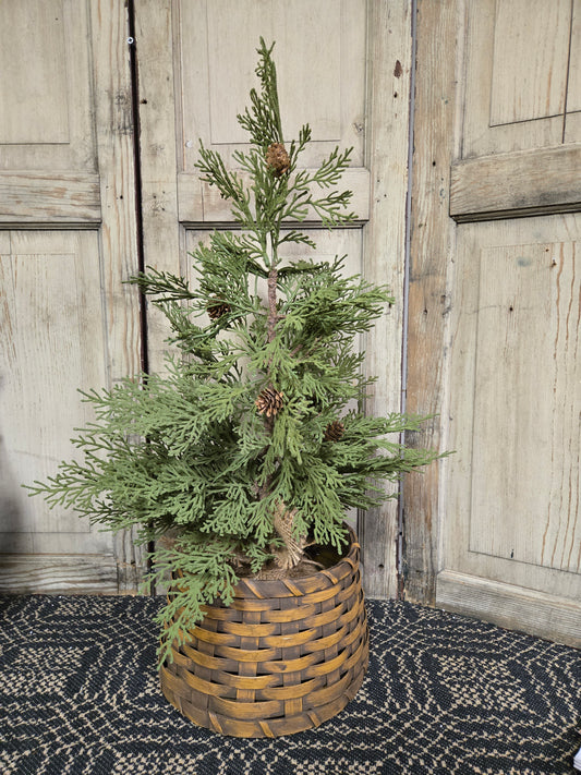 A Primitive Tree Collar in a large mustard color, displayed with a small artificial tree inside it, placed against a rustic wooden backdrop.
