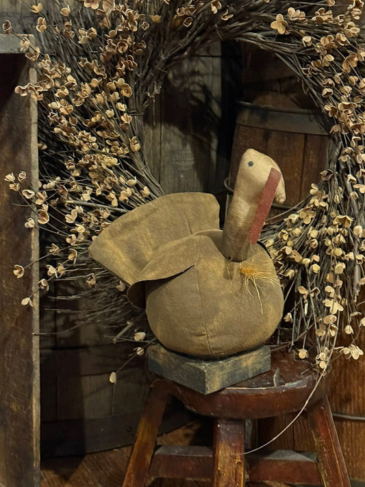Decorative turkey figure on a wooden stool with dried flowers and rustic background