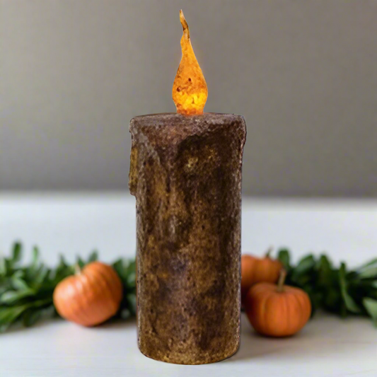 Decorative candle with a flame on a white background with pumpkins around it