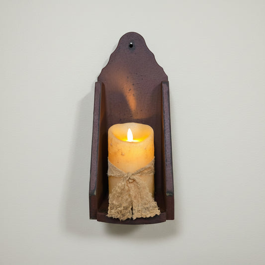 Decorative wall sconce with a lit candle on a rustic wooden background
