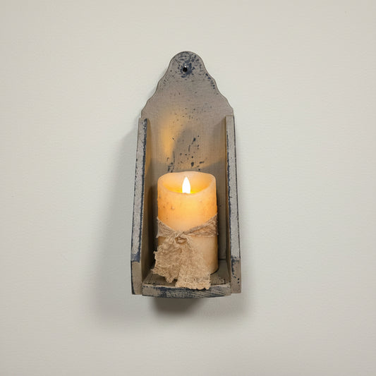 Wooden wall sconce with a lit candle on a rustic wooden background