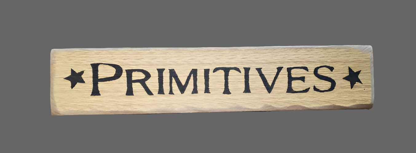 A wooden sign with the word 'Primitives' written in black on a cream background color, surrounded by a star pattern