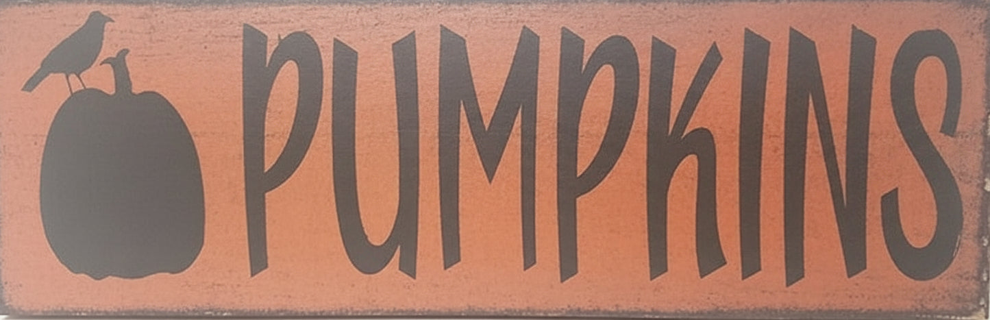 Wooden sign with 'PUMPKINS' text and pumpkin silhouette on a white background