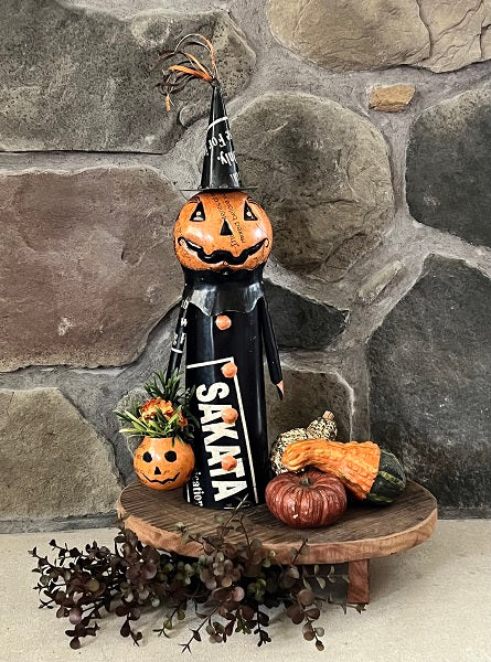 Metal pumpkin man with candy bucket made from meal standing on wood riser