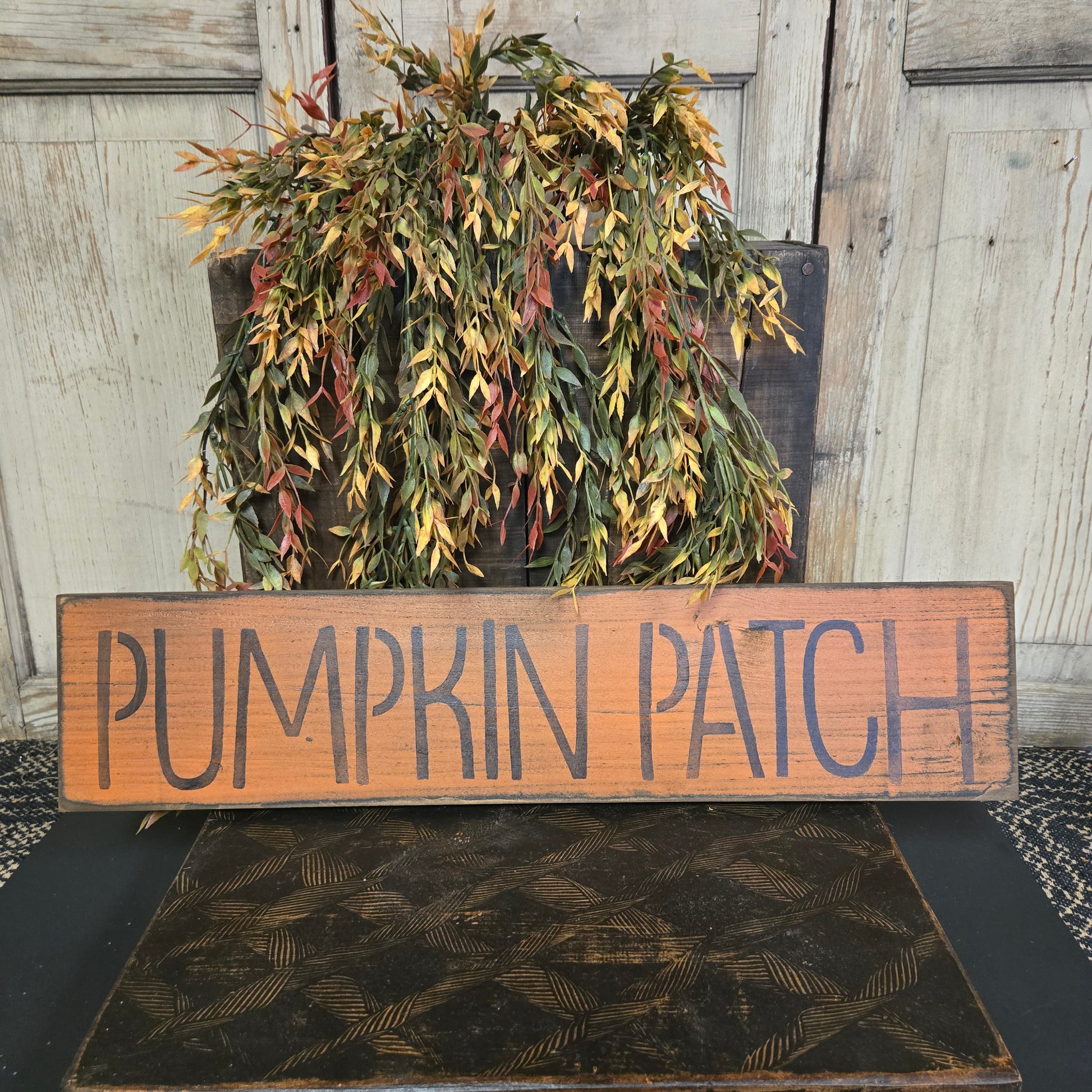 Wooden sign with 'Pumpkin Patch' text next to a wreath on a door.