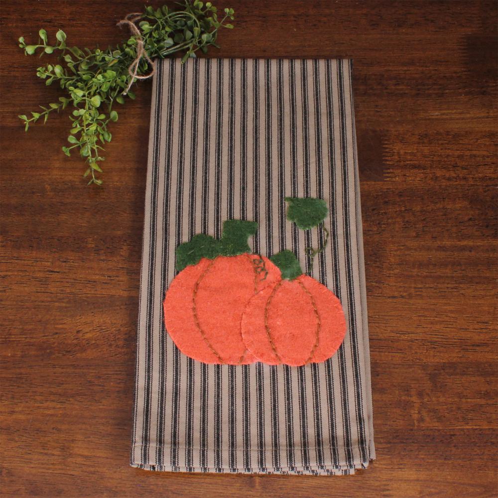 Striped towel with pumpkin applique on a wooden surface