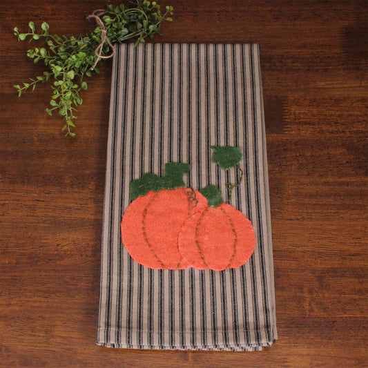 Striped towel with pumpkin applique on a wooden surface