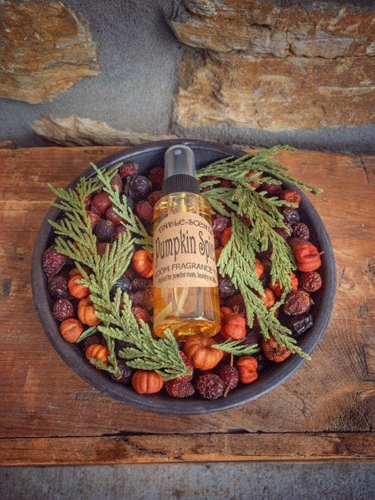 A metal pan with a pumpkin spice scent label, surrounded by potpourri and decorative autumnal items like leaves and berries.