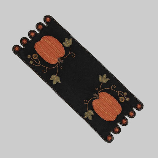 A black table runner with pumpkin designs and leaf patterns, likely made from wool felt.