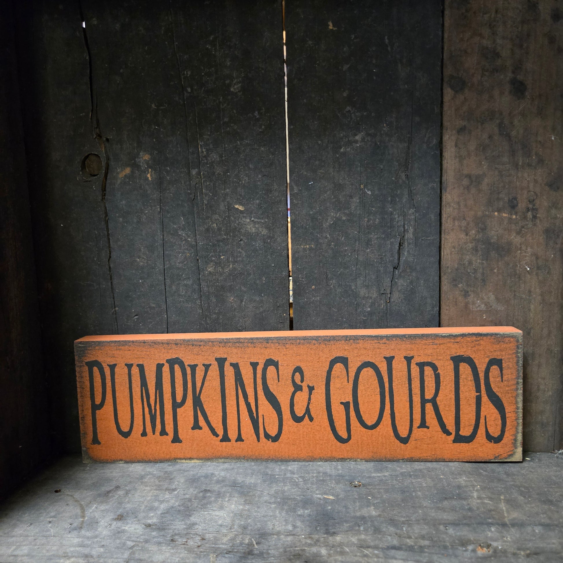 Wooden sign with 'Pumpkins & Gourds' text on a rustic wooden surface