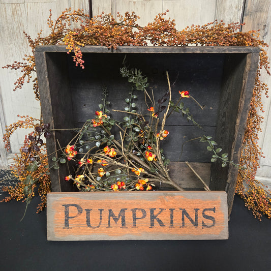 Decorative wooden box with dried flowers and a 'Pumpkins' sign on a dark background.