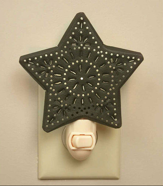 A punched star-shaped night light with a black and white design, mounted on a white wall socket, featuring a bulb and a switch.
