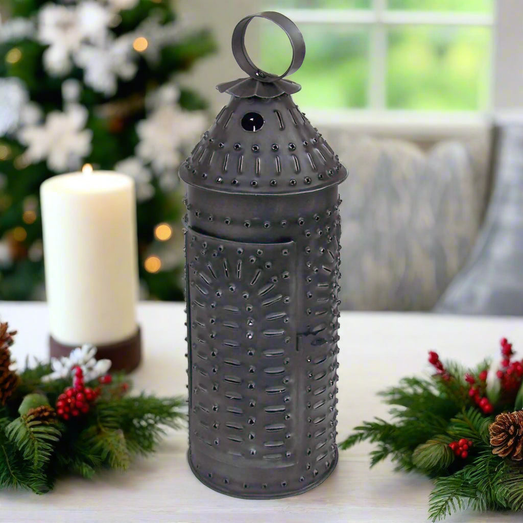 Rustic punched tin lantern with a round hanger on top and a latched door, in an antiqued gray finish.