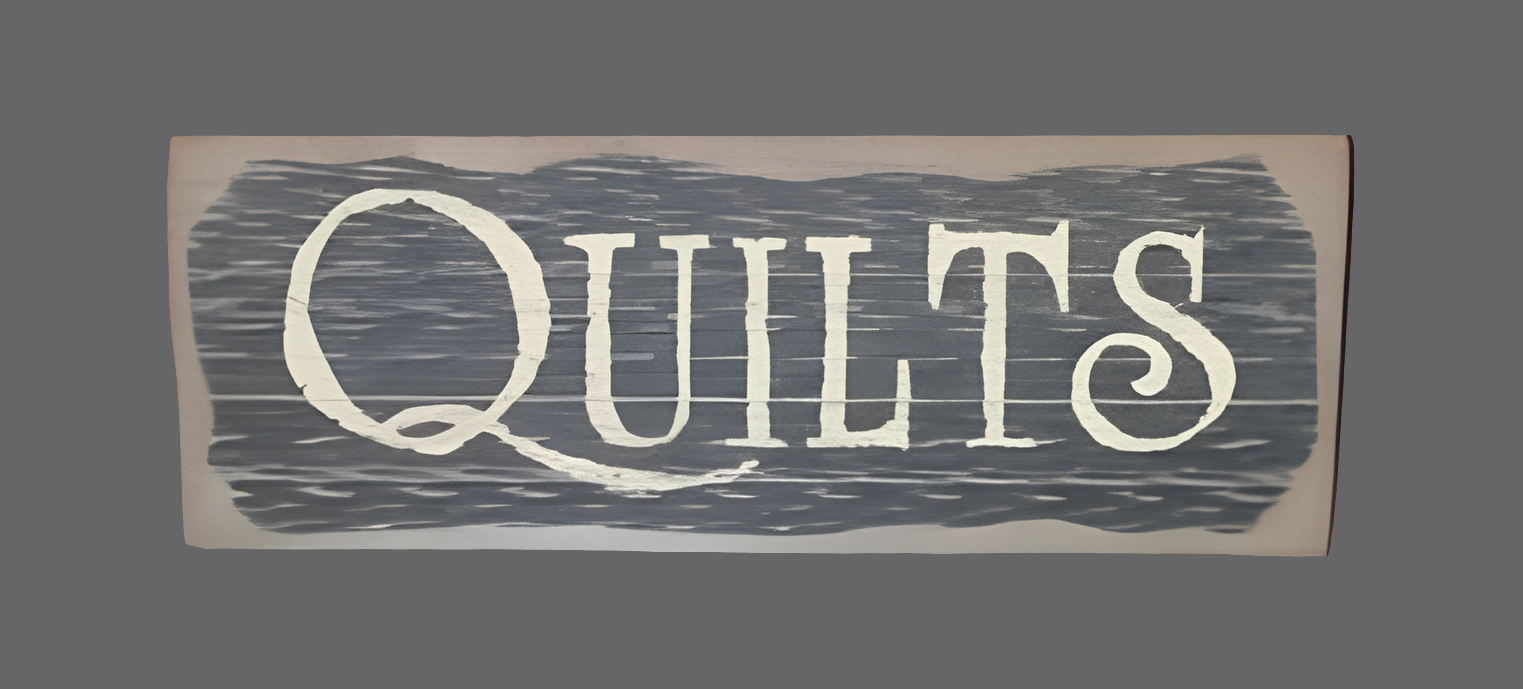A wood sign with the word 'Quilts' written in black on a cream background with a distressed look.